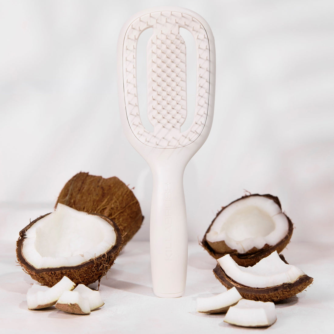 White paddle brush with coconut halves on a light gray background