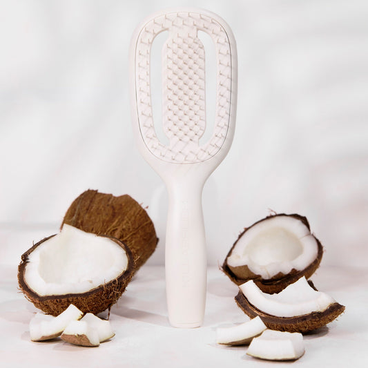 White paddle brush with coconut halves on a light gray background