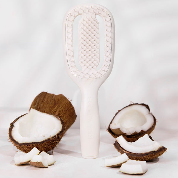 White paddle brush with coconut halves on a light gray background