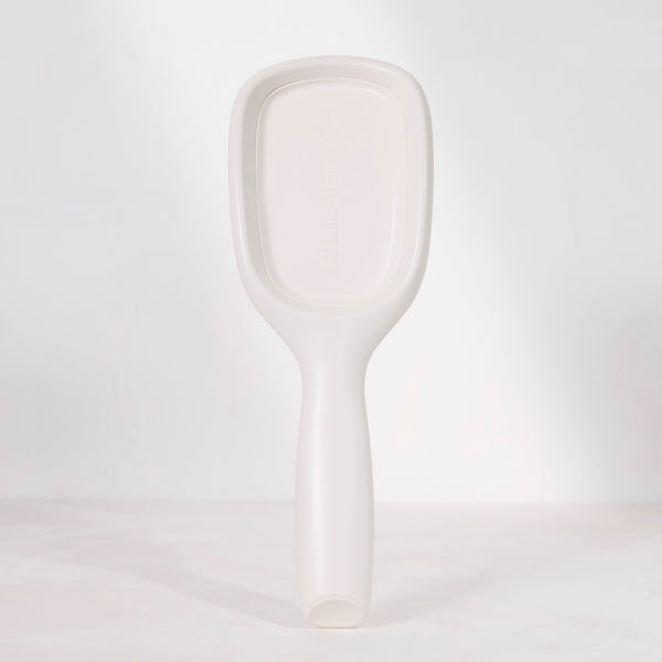 A minimalist, handleless spoon or scoop with a rounded rectangular head, shown in a solid off-white color against a clean, light gray studio background.