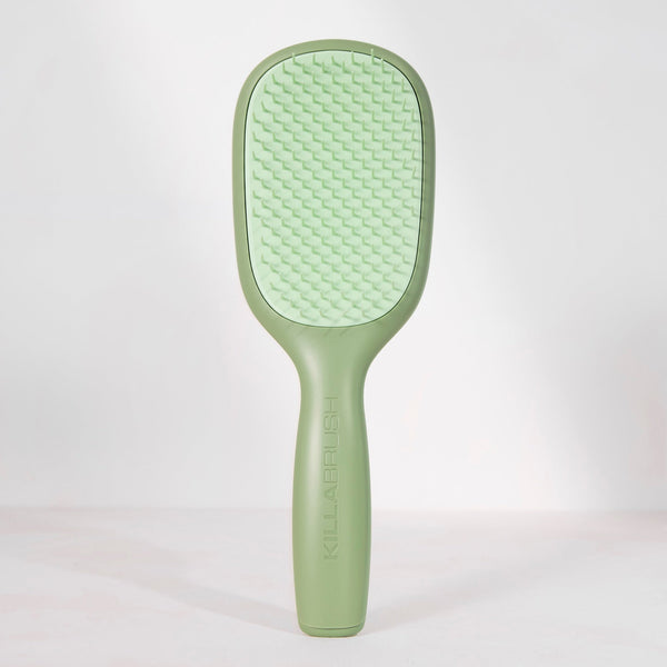 A light green hairbrush with a textured oval head and a smooth handle, standing upright against a clean white background.