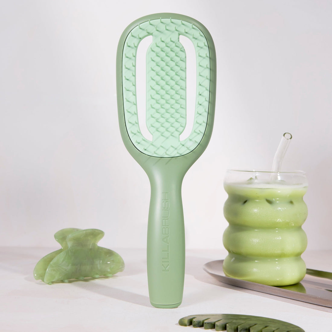 Green hairbrush and other green ceramic items on a white background