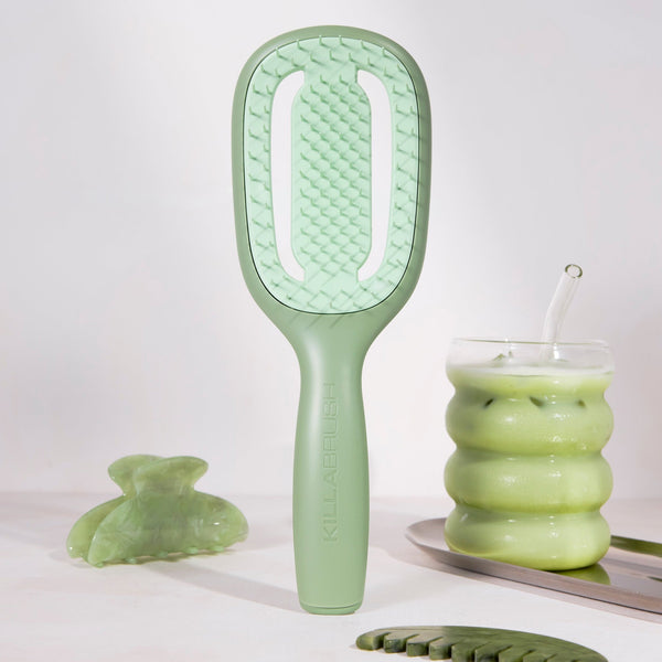 Green hairbrush and other green ceramic items on a white background