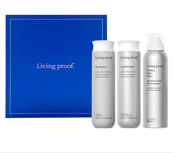 Living Proof hair care product set with shampoo, conditioner, and dry shampoo against a blue background