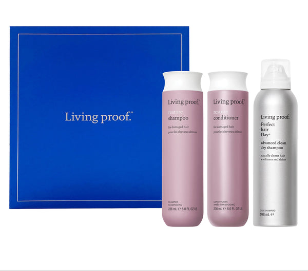 Living Proof hair care product set with shampoo, conditioner, and dry shampoo against a blue background