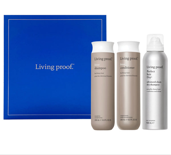 Living Proof hair care product set with shampoo, conditioner, and dry shampoo against a blue background