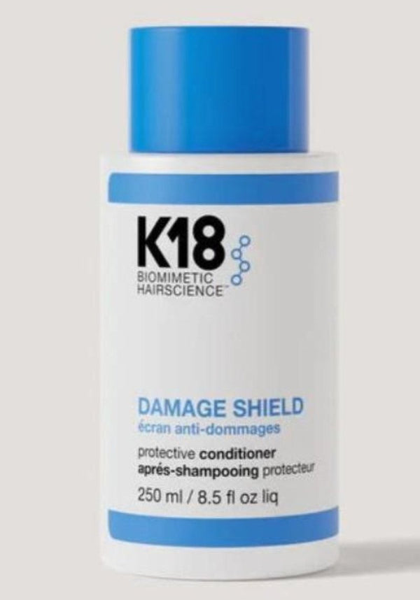 A bottle of K18 Damage Shield Protective Conditioner, 250ml size, with blue and white labeling.
